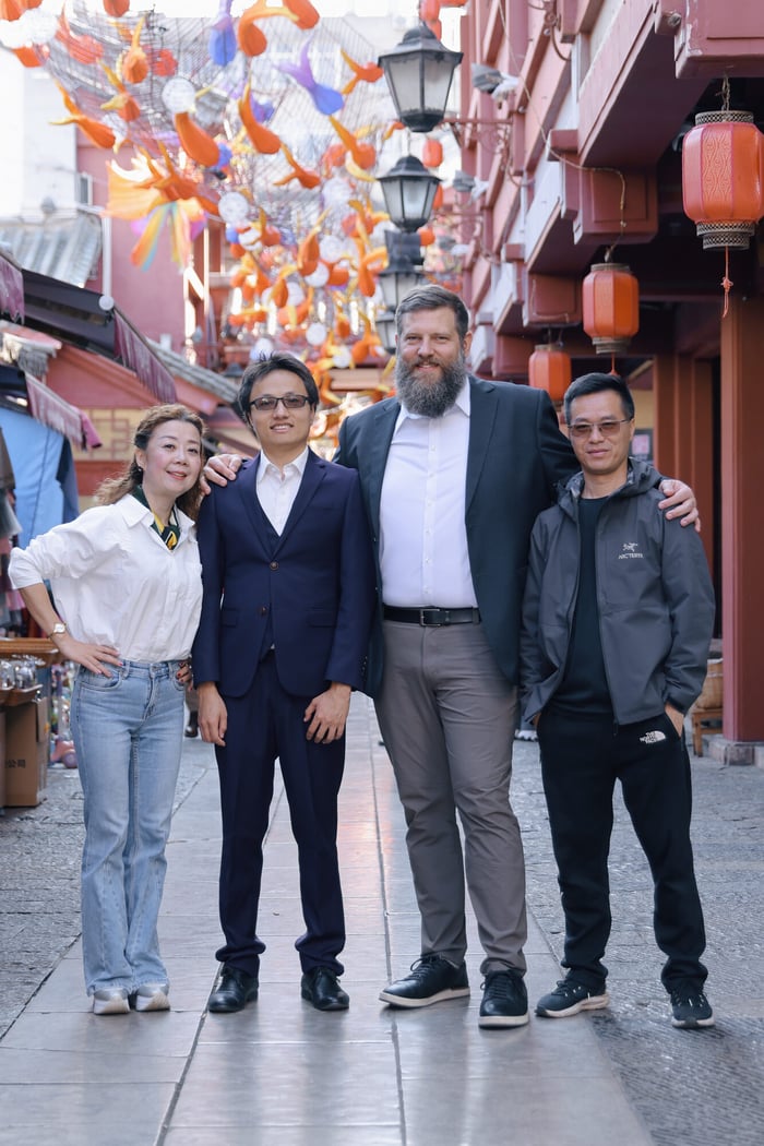 Bobby Robbins standing with three young partners on a lantern-lined street