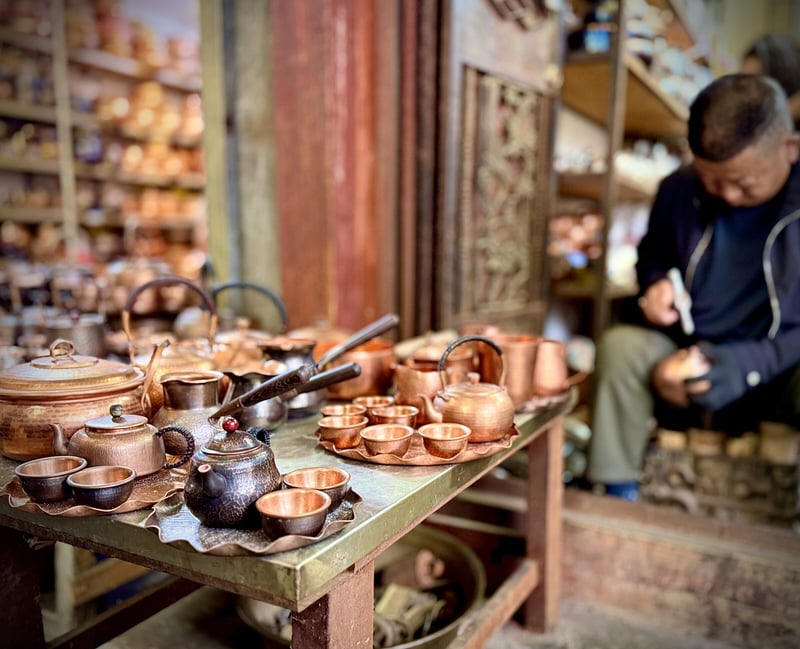 A copper craftsman at work among his teapots and bowls