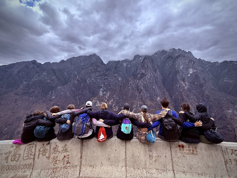 A group sitting together on a ledge above Tiger Leaping Gorge