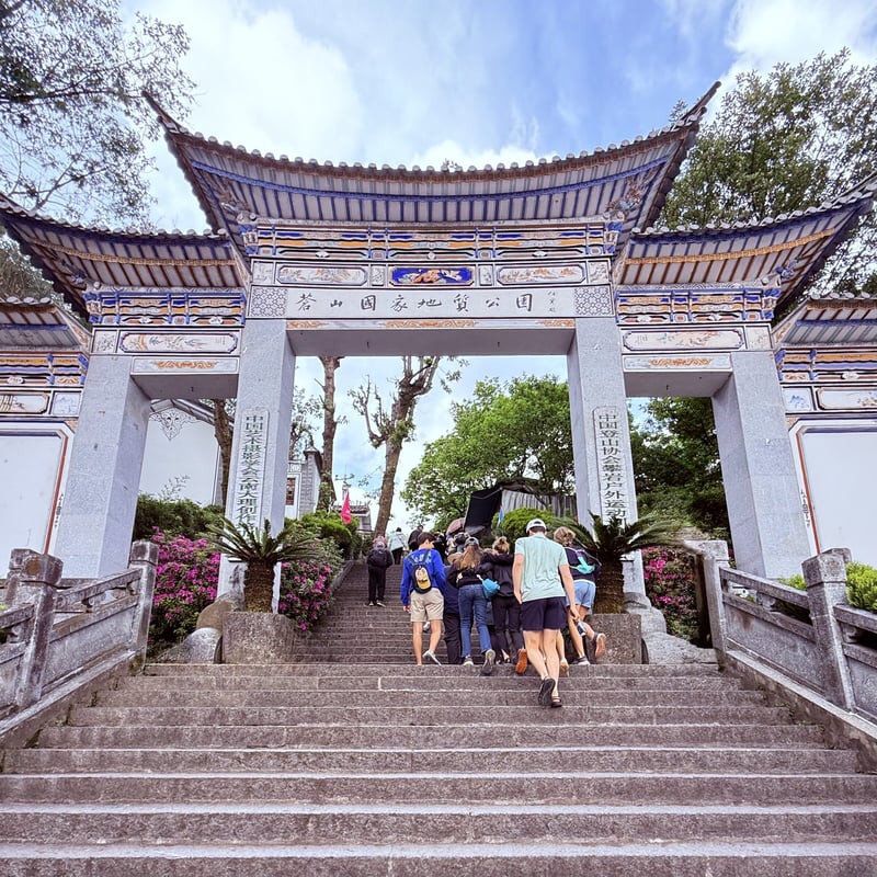 Travelers climbing the steps to an ornate temple gate