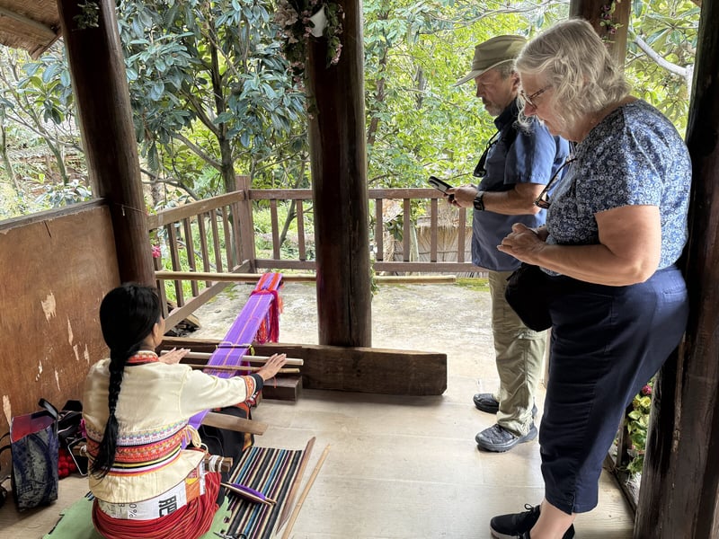 Travelers watching a village weaver at her loom