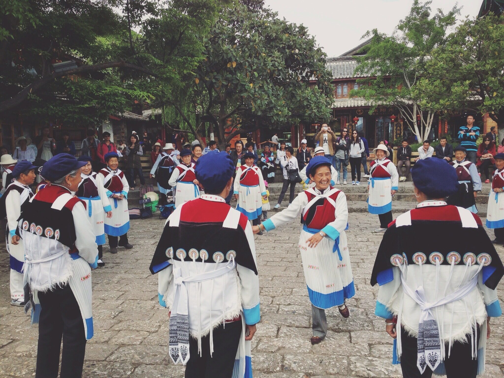 Naxi women in traditional dress dancing in a Lijiang square